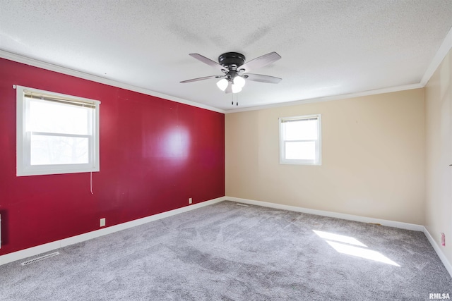 carpeted spare room featuring visible vents, a ceiling fan, crown molding, and a textured ceiling