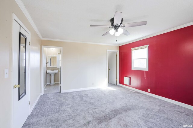 unfurnished bedroom with carpet flooring, crown molding, baseboards, and a sink