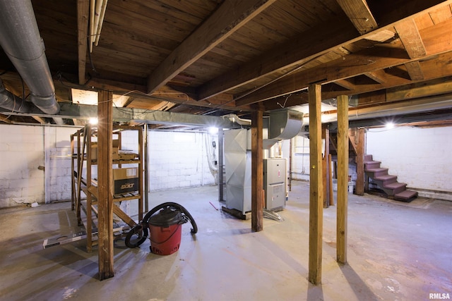 unfinished basement featuring stairway and heating unit