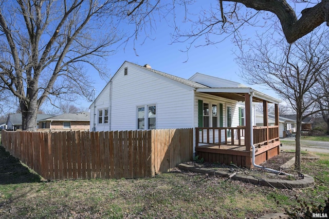 view of property exterior with a porch and fence