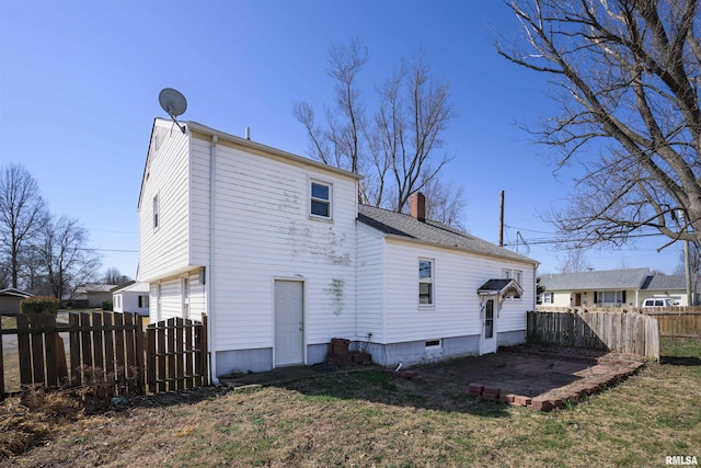 back of property featuring a yard, fence, and a chimney