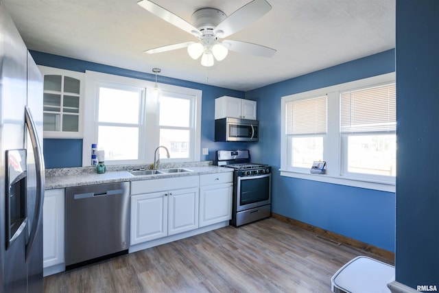 kitchen featuring white cabinets, stainless steel appliances, a ceiling fan, and a sink