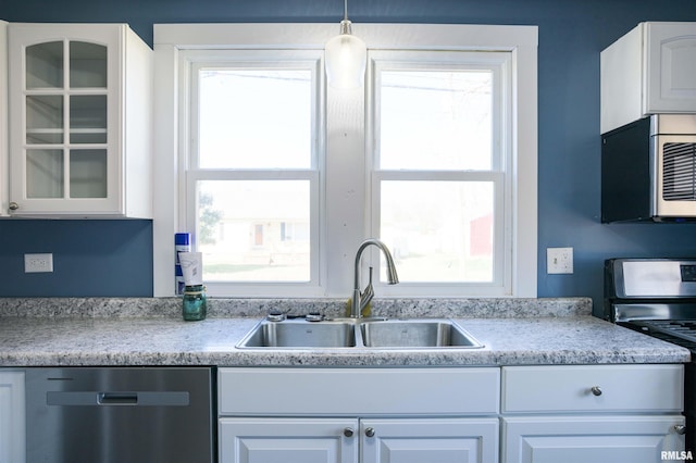 kitchen featuring white cabinetry, glass insert cabinets, appliances with stainless steel finishes, and a sink