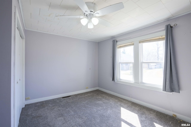 carpeted empty room with visible vents, baseboards, and ceiling fan
