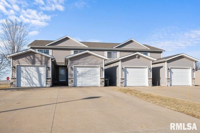 view of front facade with a garage, stone siding, and driveway