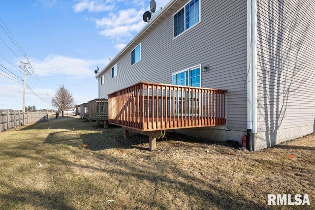 rear view of house featuring a deck, fence, and a lawn