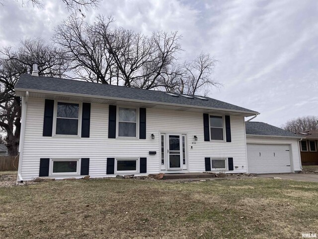 raised ranch featuring a front yard, an attached garage, and driveway