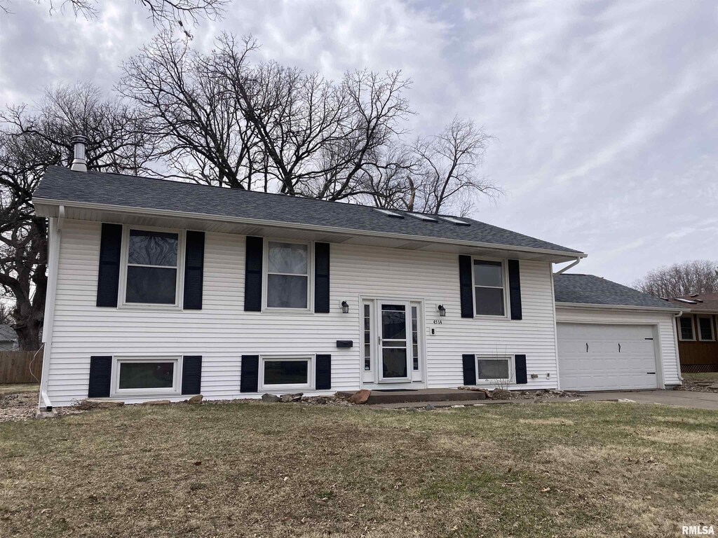 bi-level home with a front lawn, driveway, an attached garage, and roof with shingles