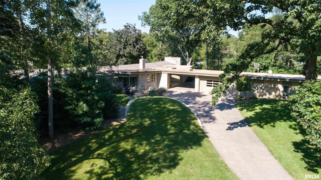 view of front facade featuring concrete driveway, a carport, a chimney, and a front yard