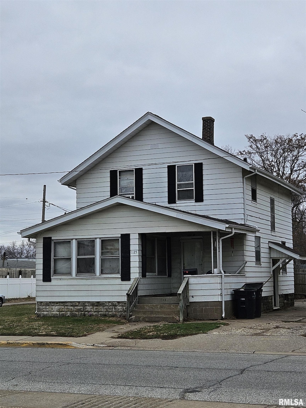 view of front of home with covered porch, a chimney, and fence
