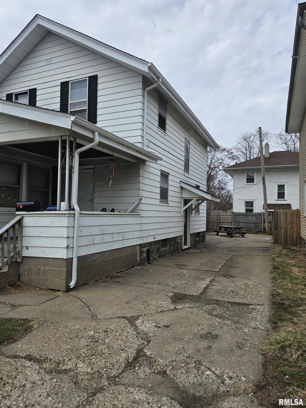 view of side of home featuring covered porch and fence