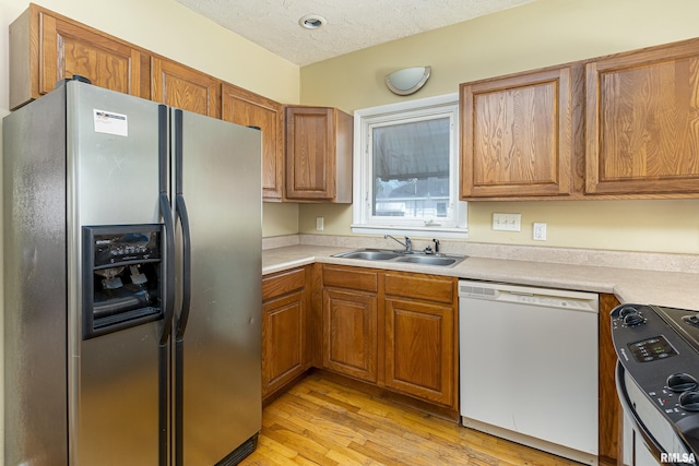 1500 W Tyler St, Herrin, IL 62948 - kitchen featuring light wood-type flooring, brown cabinets, appliances with stainless steel finishes, a textured ceiling, and a sink