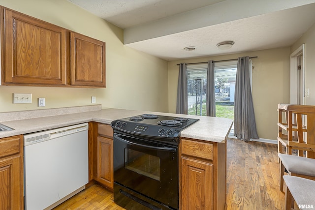 1500 W Tyler St, Herrin, IL 62948 - kitchen featuring a peninsula, black range with electric cooktop, white dishwasher, and brown cabinets