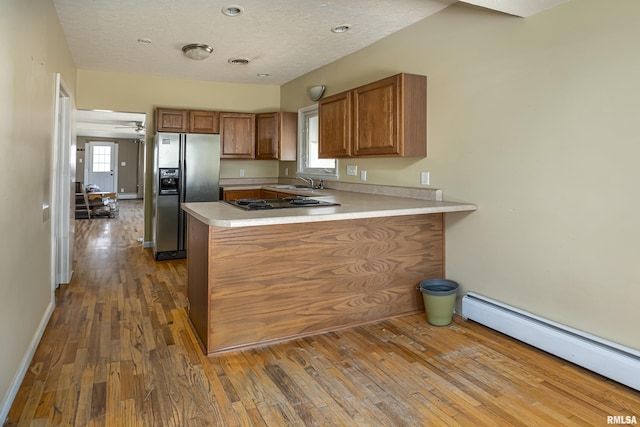 1500 W Tyler St, Herrin, IL 62948 - kitchen with a baseboard heating unit, fridge with ice dispenser, a peninsula, brown cabinetry, and wood-type flooring