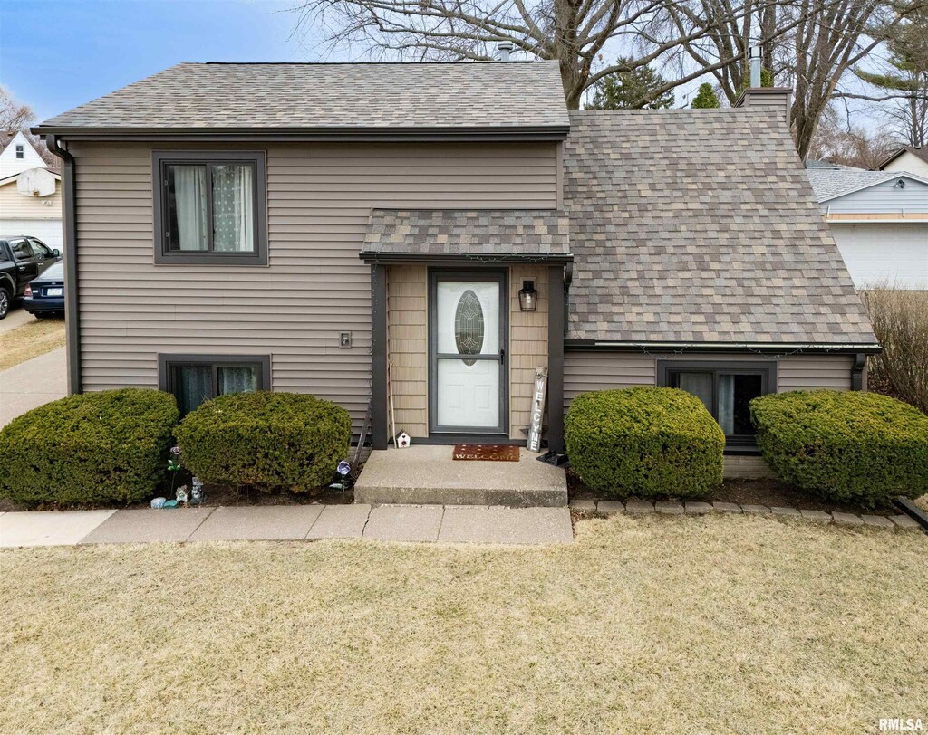 view of front of property with a front yard and a shingled roof