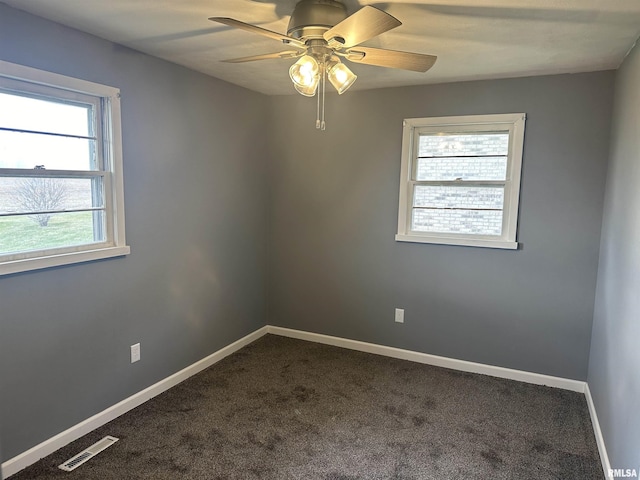 empty room featuring baseboards, visible vents, ceiling fan, and dark carpet