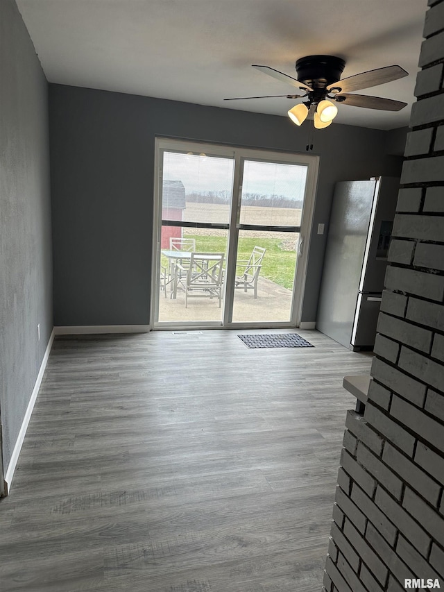 unfurnished living room with a ceiling fan, baseboards, and wood finished floors