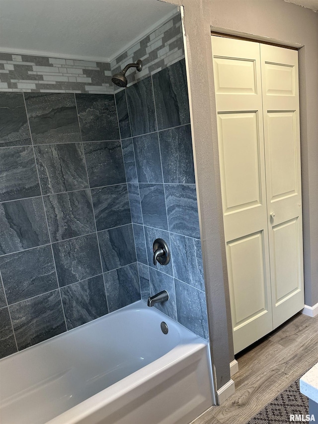 bathroom with baseboards, wood finished floors, and washtub / shower combination