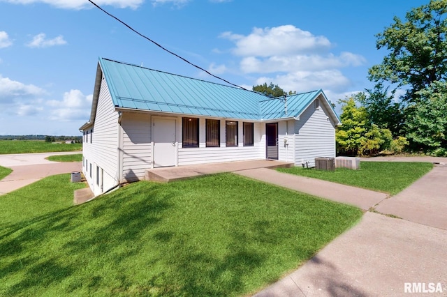 view of front of house featuring a standing seam roof, a front lawn, central AC unit, and metal roof