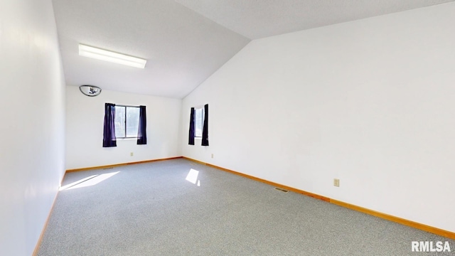 carpeted empty room featuring visible vents, baseboards, and vaulted ceiling