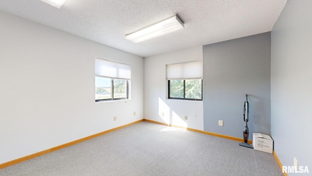 carpeted empty room featuring a textured ceiling and baseboards