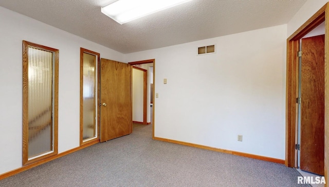 unfurnished bedroom featuring visible vents, a textured ceiling, baseboards, and carpet