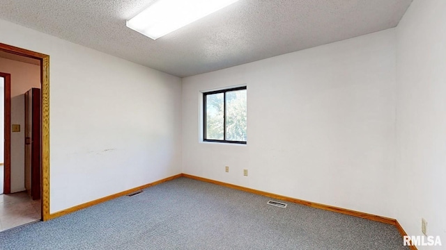 carpeted spare room with baseboards, visible vents, and a textured ceiling