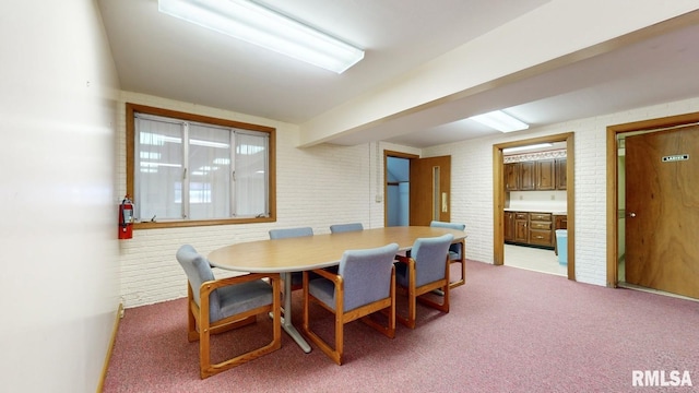dining area featuring light carpet and brick wall