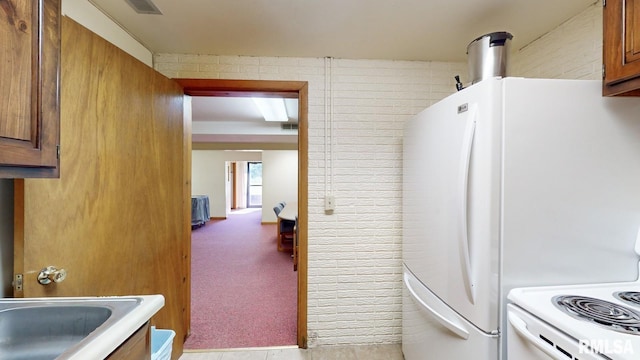 kitchen with a sink, brown cabinets, freestanding refrigerator, and carpet floors