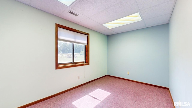 carpeted spare room with visible vents, a paneled ceiling, and baseboards