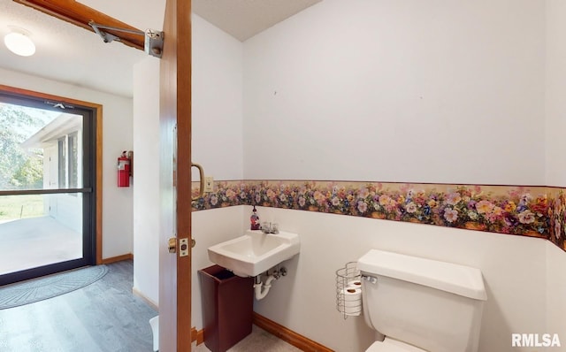 bathroom with toilet, baseboards, and wood finished floors