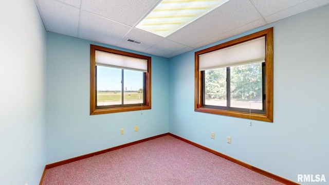 carpeted empty room with a paneled ceiling, visible vents, and baseboards