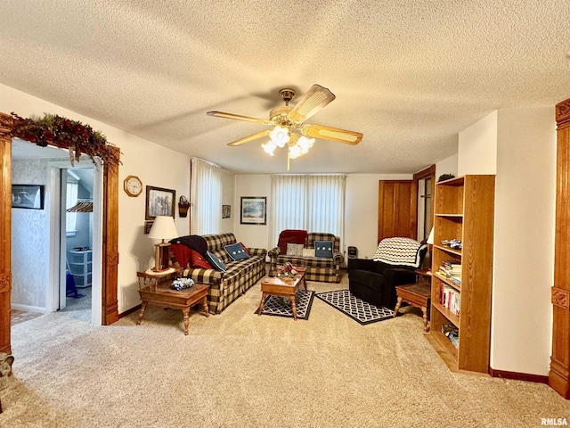 carpeted living area featuring a textured ceiling, baseboards, and ceiling fan