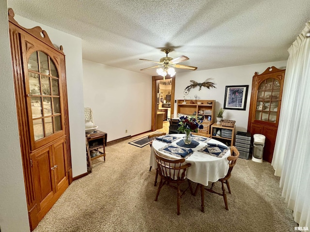 dining room with light colored carpet, a textured ceiling, baseboards, and a ceiling fan