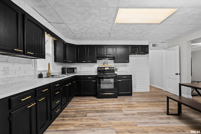 kitchen featuring stainless steel microwave, visible vents, black range with electric stovetop, light wood-style flooring, and dark cabinetry
