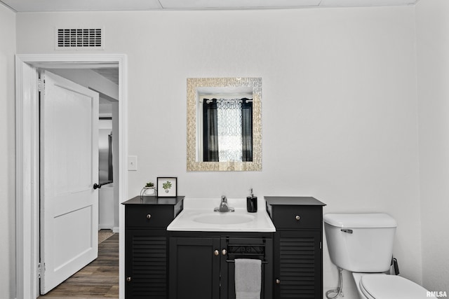 bathroom with visible vents, toilet, vanity, and wood finished floors