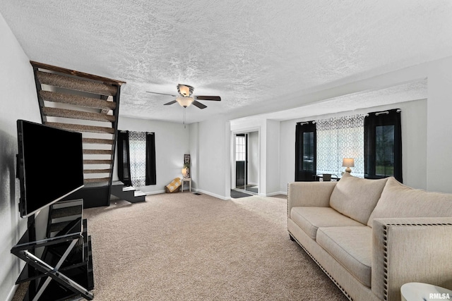 carpeted living area with baseboards, a textured ceiling, and a ceiling fan