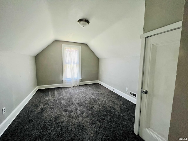additional living space with lofted ceiling, baseboards, visible vents, and dark colored carpet