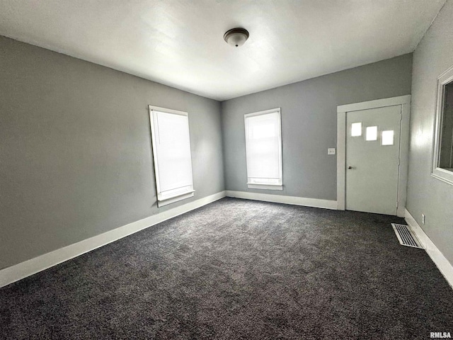 unfurnished room featuring visible vents, baseboards, and dark carpet