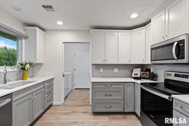19109 Bluff Rd Unit D, Geneseo, IL 61254 - kitchen with appliances with stainless steel finishes, gray cabinetry, washer and clothes dryer, light countertops, and tasteful backsplash