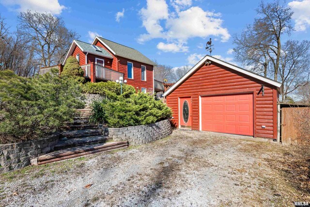 exterior space with faux log siding, an outbuilding, stairway, driveway, and a garage