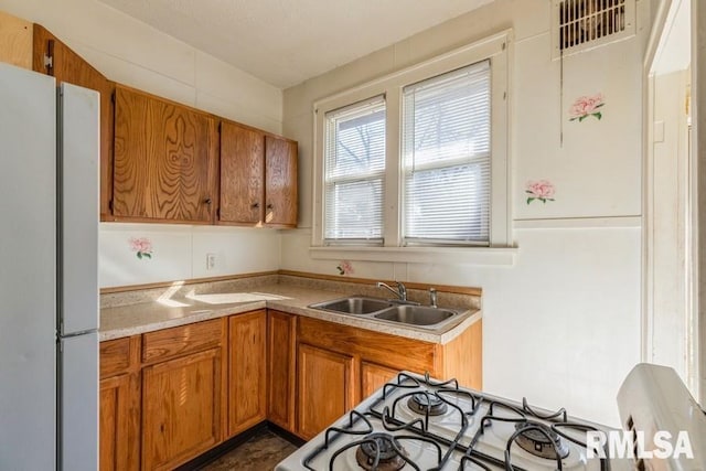 4227 11th St, Rock Island, IL 61201 - kitchen featuring light countertops, a sink, freestanding refrigerator, brown cabinets, and range with gas cooktop