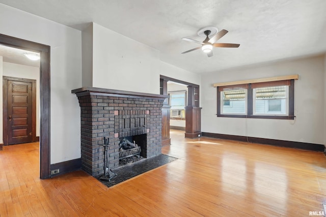 2329 Pershing Ave, Davenport, IA 52803 - unfurnished living room featuring a brick fireplace, baseboards, ceiling fan, light wood-style floors, and cooling unit