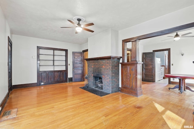 2329 Pershing Ave, Davenport, IA 52803 - unfurnished living room featuring a fireplace, baseboards, ceiling fan, and light wood-style flooring