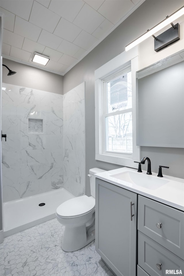 full bath with toilet, vanity, and a marble finish shower