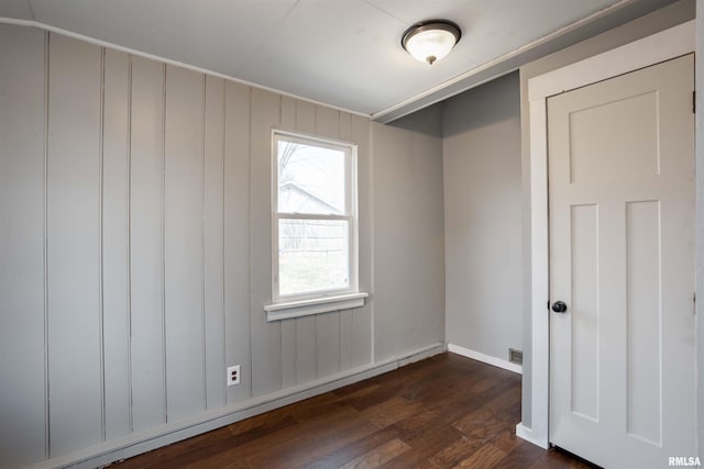 spare room with dark wood finished floors, a baseboard radiator, visible vents, and baseboards