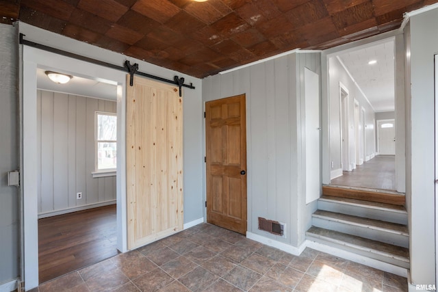 interior space featuring wooden walls, wooden ceiling, a barn door, and visible vents