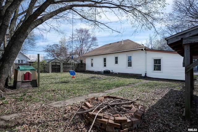 view of yard featuring central AC unit, fence, a storage unit, a fire pit, and an outdoor structure