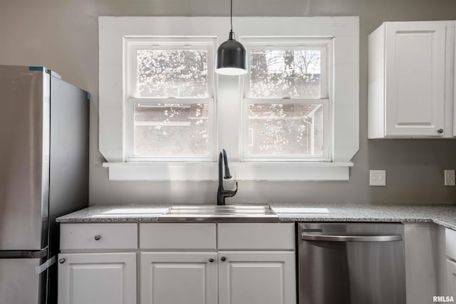 kitchen featuring pendant lighting, white cabinets, a sink, and stainless steel appliances