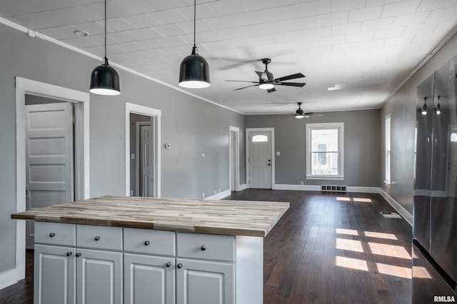 kitchen with open floor plan, butcher block countertops, ornamental molding, visible vents, and ceiling fan